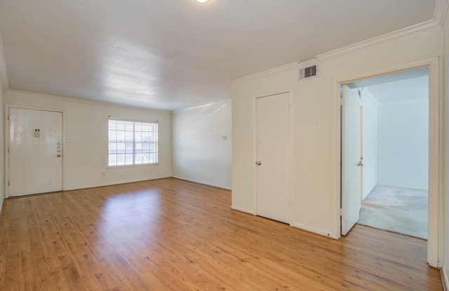 empty room with light wood-type flooring, visible vents, and crown molding