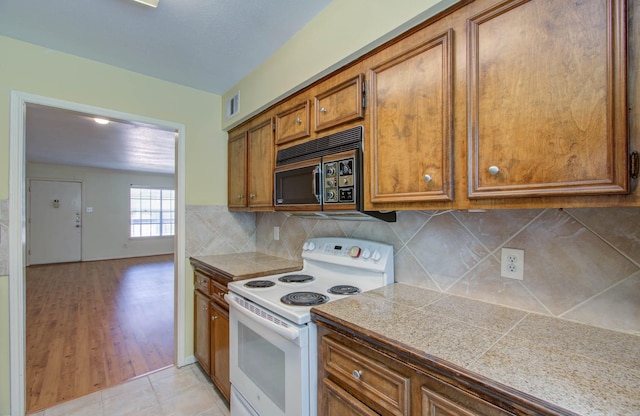 kitchen featuring tasteful backsplash, white range with electric stovetop, visible vents, tile counters, and brown cabinetry