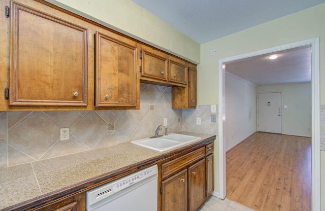 kitchen featuring white dishwasher, tile counters, brown cabinetry, and a sink