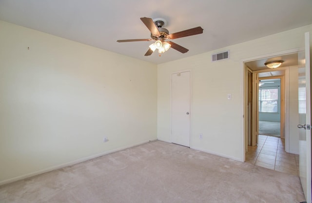 unfurnished bedroom with ceiling fan, light colored carpet, visible vents, baseboards, and a closet