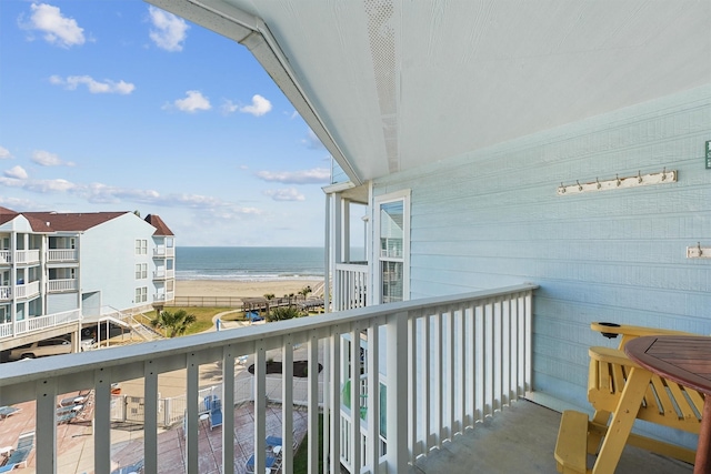 balcony with a water view and a view of the beach