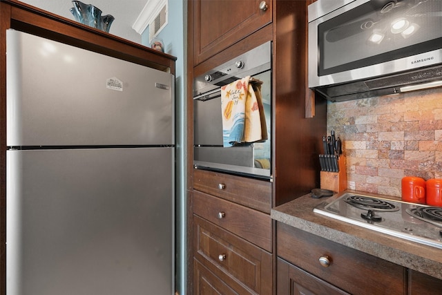 kitchen with dark brown cabinets, appliances with stainless steel finishes, dark countertops, and visible vents