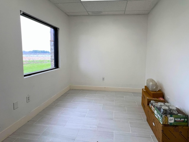 spare room featuring a drop ceiling and baseboards