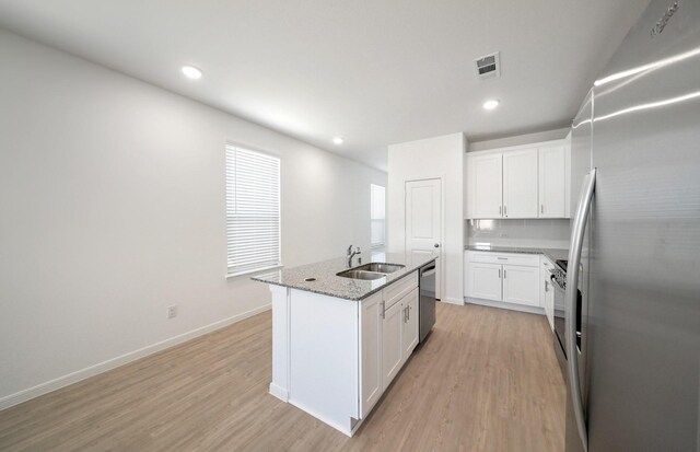 10702 Sora Dr, Willis, TX 77378 - kitchen featuring visible vents, a sink, stainless steel appliances, light wood-style floors, and white cabinets