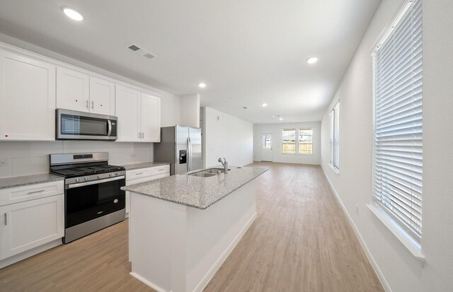 10702 Sora Dr, Willis, TX 77378 - kitchen featuring visible vents, a sink, light wood-style floors, appliances with stainless steel finishes, and white cabinets