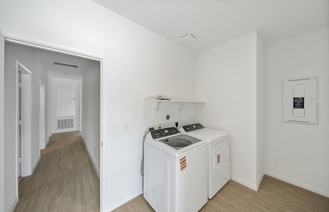10702 Sora Dr, Willis, TX 77378 - clothes washing area with visible vents, washer and clothes dryer, electric panel, light wood finished floors, and laundry area