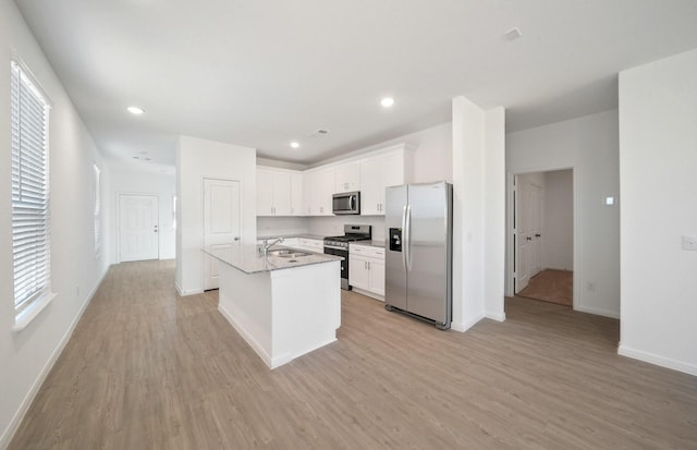 10702 Sora Dr, Willis, TX 77378 - kitchen with light wood finished floors, white cabinetry, stainless steel appliances, and a sink