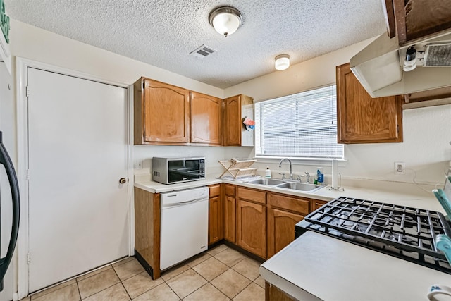 kitchen featuring range hood, light countertops, visible vents, white dishwasher, and a sink