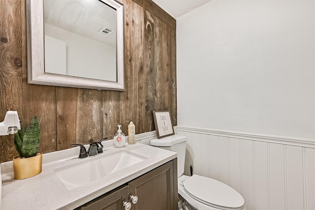 bathroom with wainscoting, visible vents, vanity, and toilet