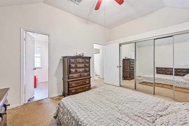 bedroom featuring a closet, ensuite bathroom, light carpet, vaulted ceiling, and a textured ceiling