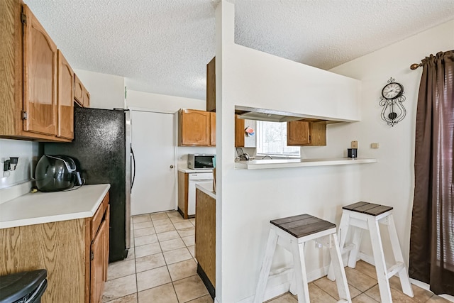 kitchen featuring light countertops, a breakfast bar, light tile patterned flooring, and brown cabinets