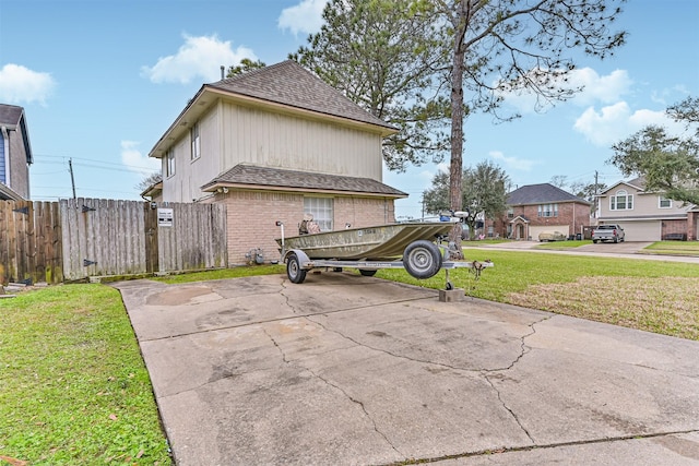 view of property exterior featuring a lawn, concrete driveway, roof with shingles, fence, and brick siding