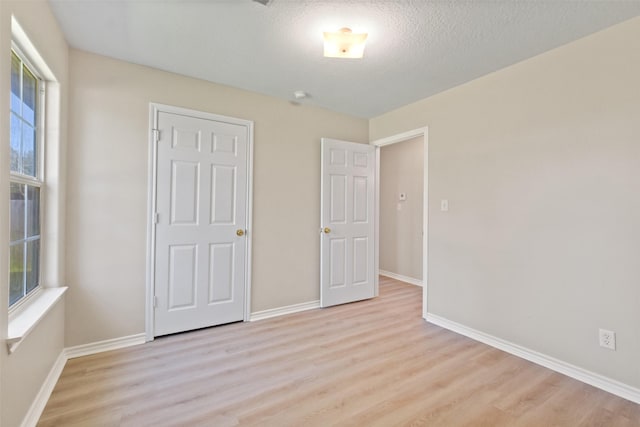 unfurnished bedroom with light wood finished floors, multiple windows, and baseboards