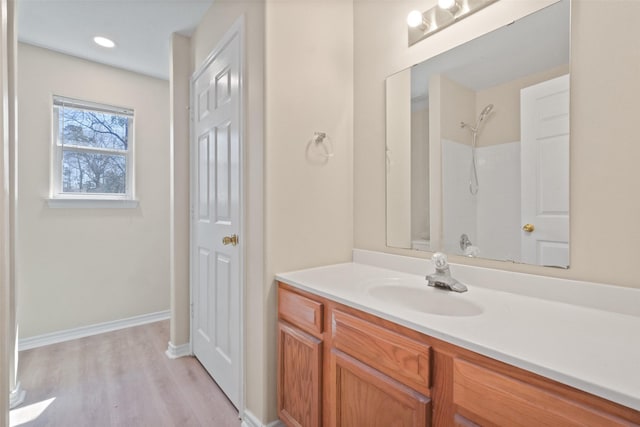 full bath with recessed lighting, wood finished floors, vanity, and baseboards