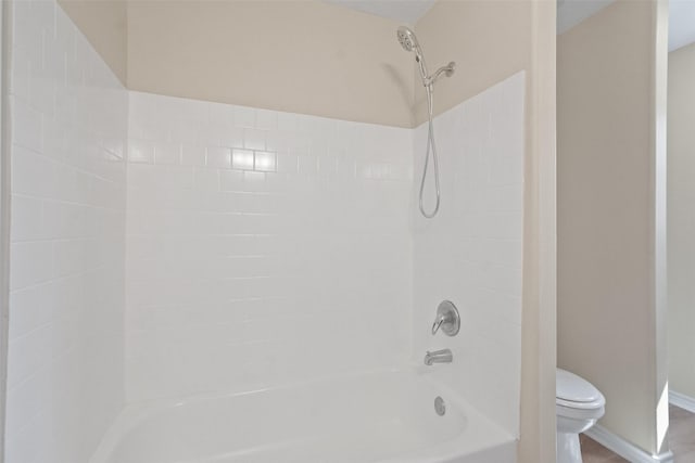 bathroom featuring shower / washtub combination, toilet, and baseboards