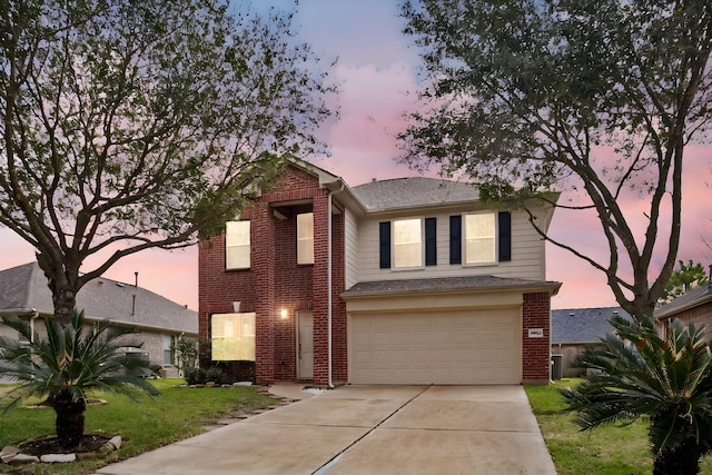 traditional-style home featuring an attached garage, a front yard, concrete driveway, and brick siding