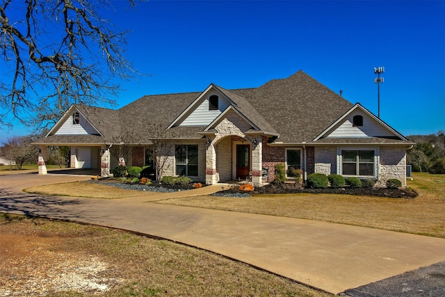 craftsman-style home with driveway, stone siding, roof with shingles, and a front yard