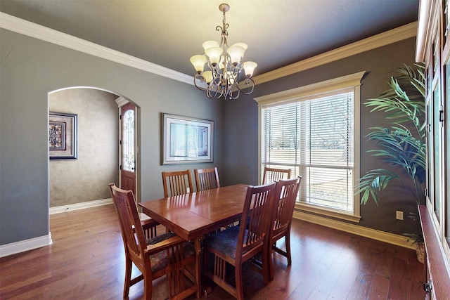 dining room with baseboards, arched walkways, dark wood finished floors, and ornamental molding