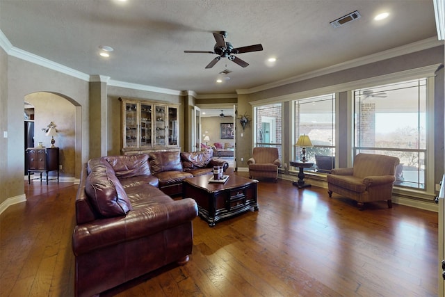 living room featuring arched walkways, dark wood-type flooring, plenty of natural light, and visible vents