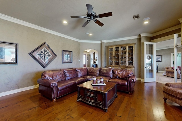 living room with dark wood-style floors, baseboards, visible vents, and arched walkways