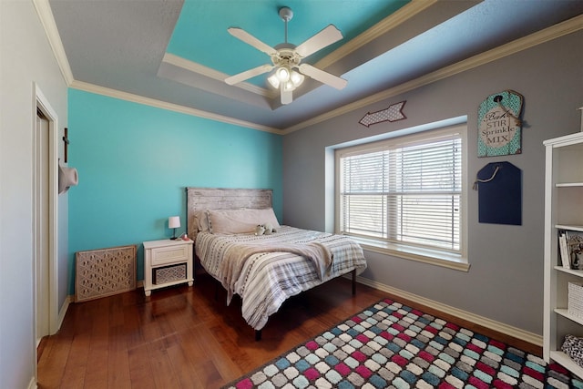 bedroom with baseboards, dark wood-style floors, ceiling fan, ornamental molding, and a tray ceiling