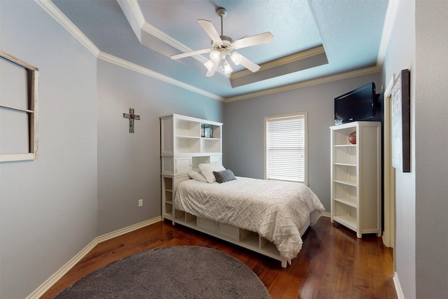 bedroom featuring crown molding, dark wood finished floors, a raised ceiling, ceiling fan, and baseboards