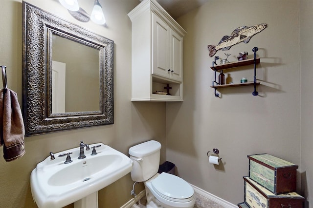 bathroom featuring toilet, baseboards, and a sink