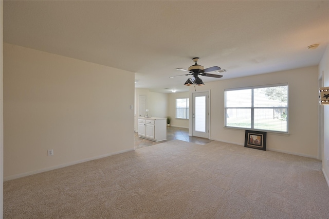 unfurnished living room featuring light carpet, visible vents, baseboards, and a ceiling fan