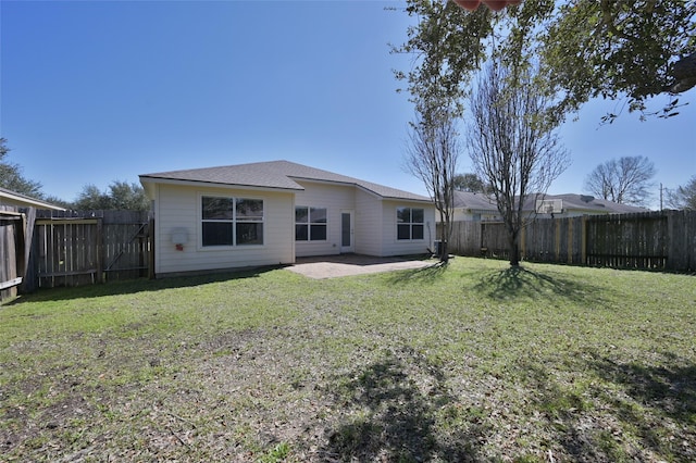 rear view of property featuring a patio area, a fenced backyard, roof with shingles, and a yard