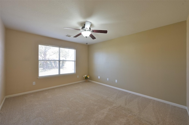 carpeted empty room with visible vents, baseboards, and a ceiling fan