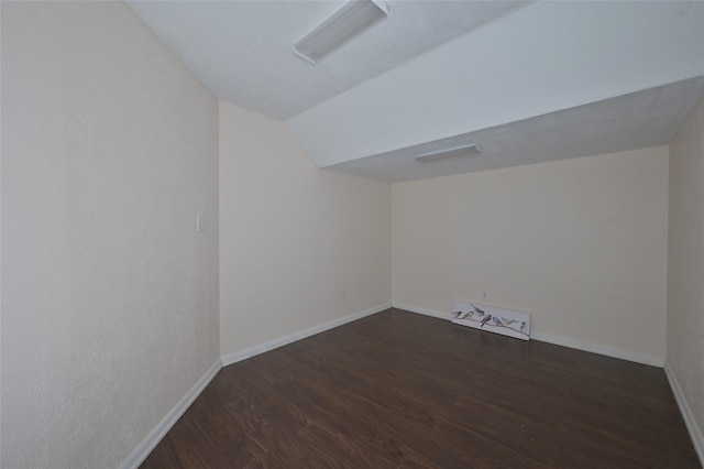 unfurnished room with lofted ceiling, baseboards, and dark wood finished floors