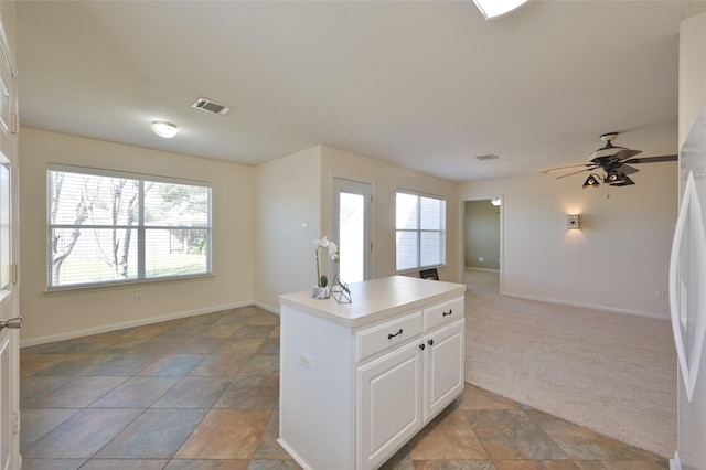 kitchen featuring light carpet, visible vents, open floor plan, light countertops, and white cabinetry