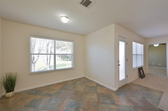 foyer entrance featuring baseboards, visible vents, and dark carpet