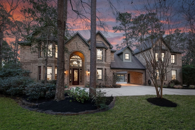 view of front of house with a shingled roof, a front yard, concrete driveway, and brick siding