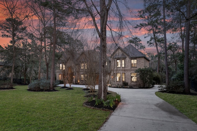 view of front facade with brick siding, a lawn, and driveway