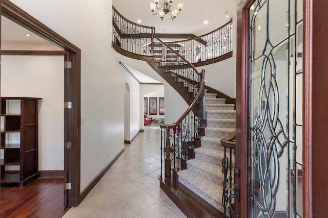 entryway featuring stairs, arched walkways, an inviting chandelier, baseboards, and tile patterned floors