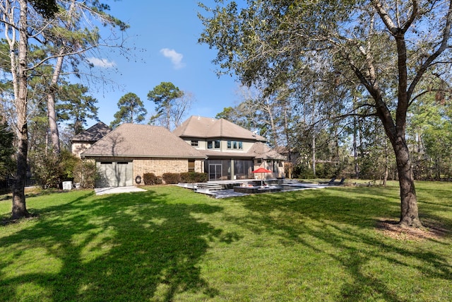 back of property with a yard, brick siding, a patio area, and a sunroom