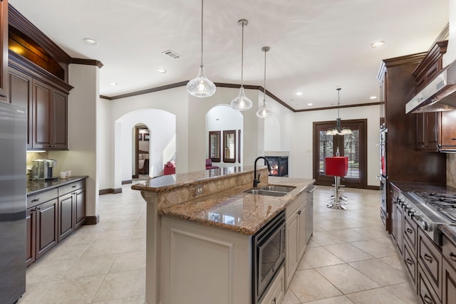 kitchen featuring light tile patterned floors, arched walkways, visible vents, stainless steel appliances, and a sink