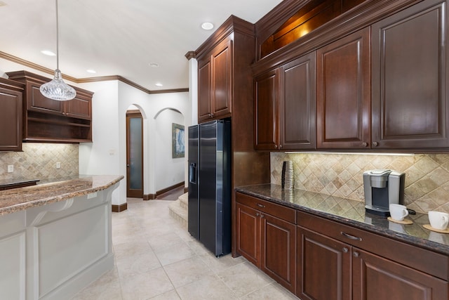 kitchen with arched walkways, decorative light fixtures, open shelves, black refrigerator with ice dispenser, and baseboards