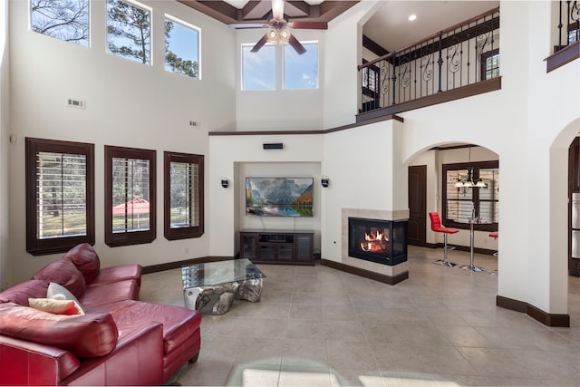 living room with visible vents, baseboards, arched walkways, a ceiling fan, and a multi sided fireplace