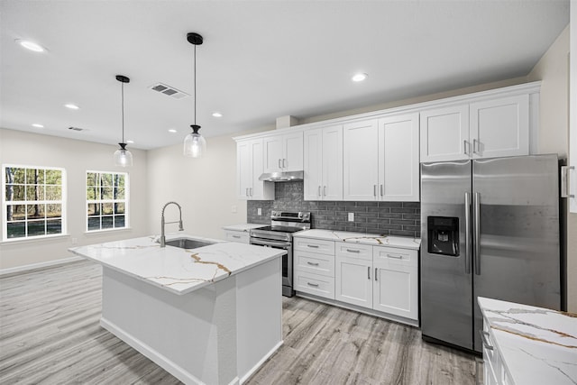 kitchen featuring stainless steel appliances, under cabinet range hood, a center island with sink, and white cabinets