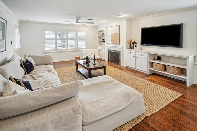 living area with a fireplace with flush hearth, ornamental molding, dark wood finished floors, and baseboards