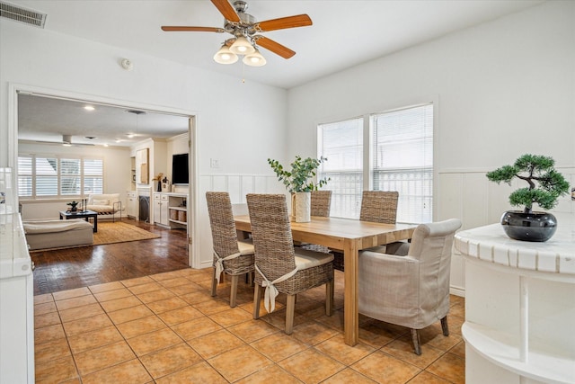 dining area with a wainscoted wall, visible vents, and light tile patterned floors