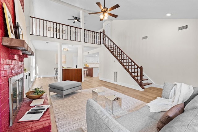 living room featuring visible vents, a fireplace, light wood finished floors, and stairs