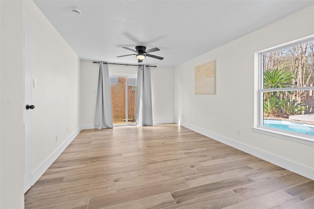 empty room featuring ceiling fan, light wood finished floors, and baseboards