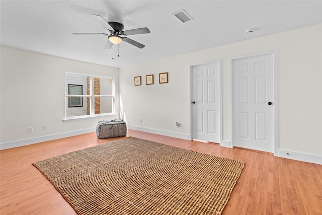 interior space with ceiling fan, baseboards, visible vents, and light wood-style floors