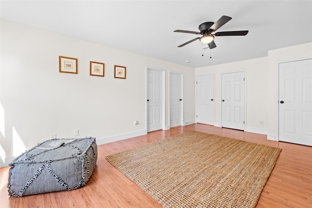 bedroom featuring multiple closets, ceiling fan, baseboards, and wood finished floors