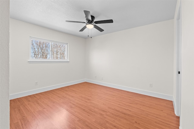 empty room with baseboards, a ceiling fan, and light wood-style floors