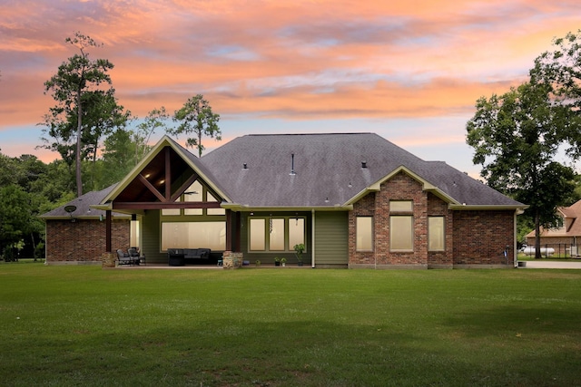 exterior space featuring a patio area, a lawn, an outdoor living space, and brick siding