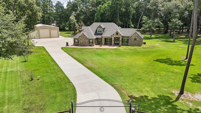 exterior space with a garage, stone siding, a gate, an outdoor structure, and a front yard